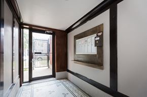 Chicago apartment for rent - a view of a hallway with a glass door and a bulletin board on the wall