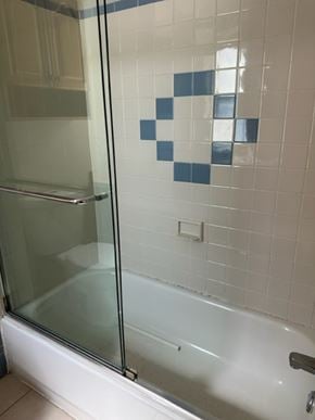 Philaladephia house for rent - A white bathtub with a glass shower door in a bathroom.