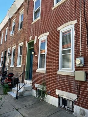 Philaladephia house for rent - A red brick building with a green door and a mailbox on the right side.