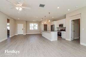 Palm Bay house for rent - an empty living room with a kitchen and a ceiling fan