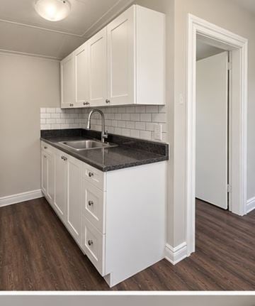 London apartment for rent - A kitchen with white cabinets and a black countertop.