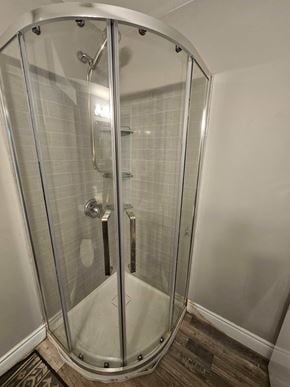 London apartment for rent - A shower stall with a glass door and a brown floor.