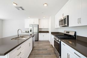 Desert Hot Springs house for rent - a modern kitchen with white cabinets and black counter tops