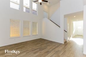 Fort Worth house for rent - an empty living room with white walls and wood floors and a ceiling fan