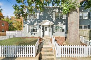 Washington apartment for rent - a blue house with a white picket fence and a large tree