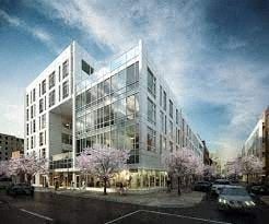 Newark apartment for rent - A modern building with a glass facade is surrounded by trees with pink blossoms.
