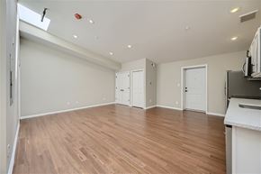 Baltimore apartment for rent - A spacious room with wooden flooring and white walls.