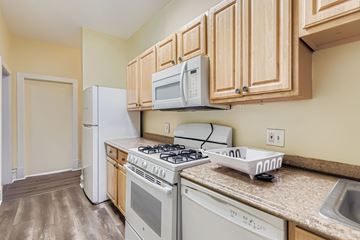 Baltimore apartment for rent - A kitchen with a white stove top oven and a white microwave above it.
