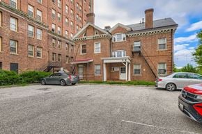 Baltimore apartment for rent - A parking lot with cars and a red brick building.