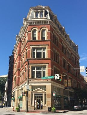 Baltimore apartment for rent - A tall red brick building with a green awning on the corner of a street.