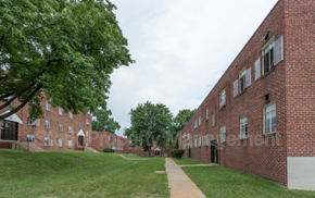 Baltimore apartment for rent - an exterior view of two brick buildings with grass and trees