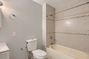 Baltimore apartment for rent - A white toilet is next to a bathtub in a bathroom.