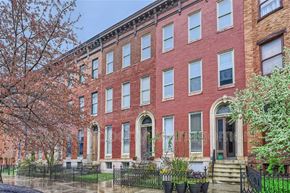 Baltimore apartment for rent - A red brick building with a black fence in front.