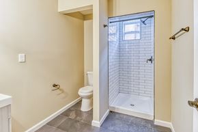 Baltimore apartment for rent - A white toilet sits in a bathroom with a walk-in shower.