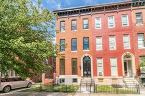 Baltimore apartment for rent - A red brick building with a black gate in front.
