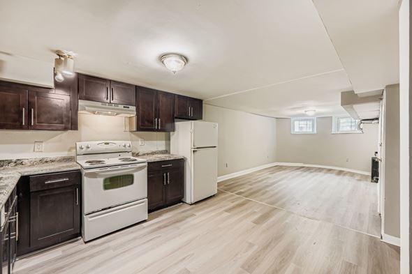 Baltimore apartment for rent - A kitchen with white appliances and brown cabinets.