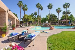 Las Vegas apartment for rent - a pool with lounge chairs and a water fountain and palm trees