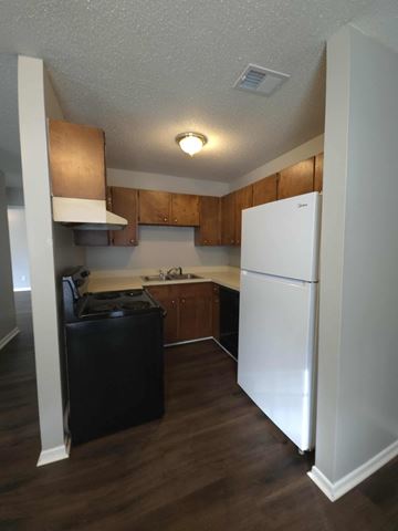 Hattiesburg apartment for rent - A kitchen with a white refrigerator and wooden cabinets.