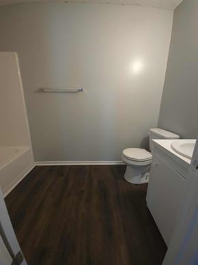 Hattiesburg apartment for rent - A white toilet sits in a bathroom with wood flooring.