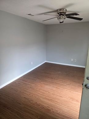 Hattiesburg apartment for rent - A room with a ceiling fan and wooden flooring.