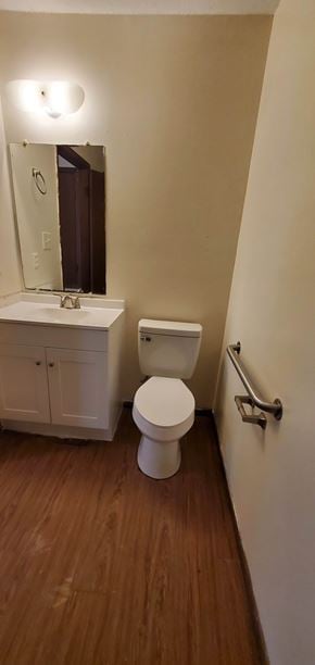 Hattiesburg apartment for rent - A white toilet sits in a bathroom next to a white cabinet and a mirror.