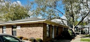 Hattiesburg apartment for rent - A small brick house with a porch and a car parked in front.