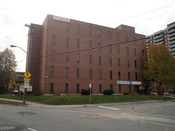 Ottawa apartment for rent - A large red brick building with a white sign on the front.