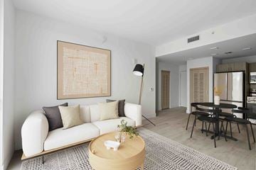 Miami apartment for rent - A living room with a white couch and a large abstract painting on the wall.