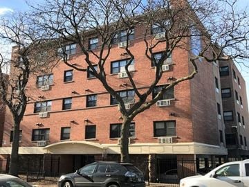 Chicago apartment for rent - A tall brick building with a tree in front of it.