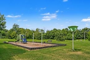 Murfreesboro apartment for rent - A playground with a slide, swings, and a bench is surrounded by trees.