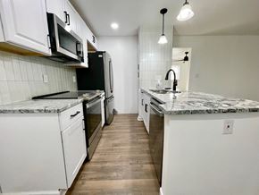 Louisville house for rent - an empty kitchen with marble counter tops and white cabinets