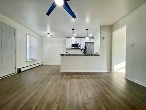Louisville house for rent - an empty living room with a kitchen in the background and a ceiling fan