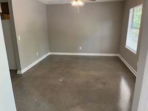 Newnan house for rent - A room with a grey floor and a chandelier hanging from the ceiling.