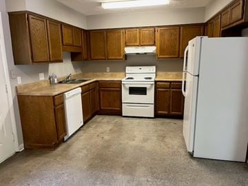 Newnan house for rent - A kitchen with brown cabinets and white appliances.