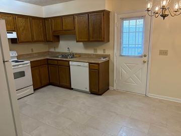 Newnan house for rent - A kitchen with wooden cabinets and a white door.