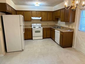 Newnan house for rent - A kitchen with white appliances and wooden cabinets.