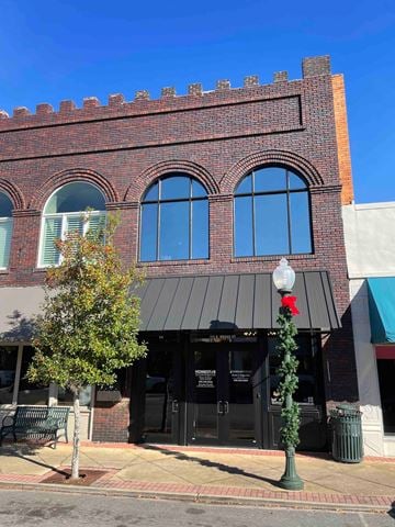 Bainbridge house for rent - A red brick building with a black awning and a green tree in front.