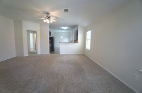 Royse City house for rent - A spacious room with a ceiling fan and carpeted floor.