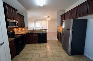 Royse City house for rent - A kitchen with a black refrigerator and black countertops.