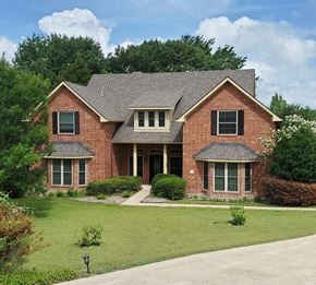 Rockwall house for rent - A red brick house with a grey roof and a green lawn in front.