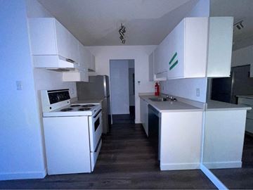Vancouver apartment for rent - an empty kitchen with white cabinets and a stove