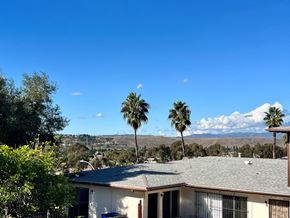 Oceanside apartment for rent - a house with palm trees in front of it and mountains in the distance