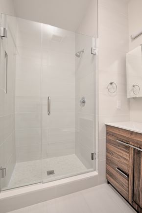 Nyack apartment for rent - A modern bathroom with a walk-in shower and a wooden cabinet.