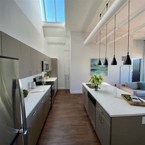 Hartford apartment for rent - A modern kitchen with a refrigerator on the left and a dining area with a couch in the background.