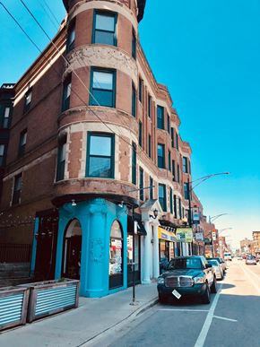 Chicago apartment for rent - A street view of a row of buildings with a car parked on the side.
