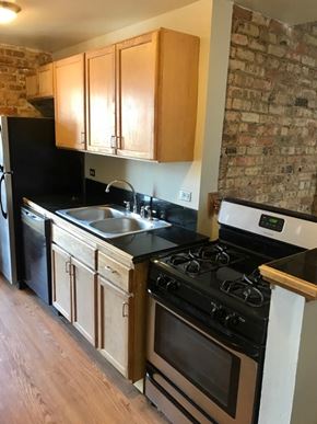 Chicago apartment for rent - A kitchen with wooden cabinets and a black fridge.