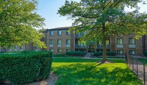 Capitol Heights apartment for rent - a large brick apartment building with a grass yard and trees