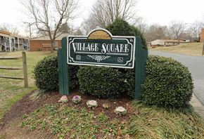Gastonia apartment for rent - a sign for village square in front of some bushes
