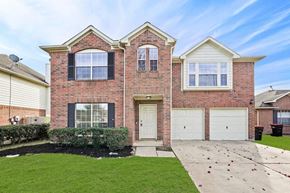 Katy house for rent - the front of a brick house with two garage doors