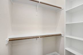 Hondo house for rent - a walk in closet with white shelves and a wooden shelf